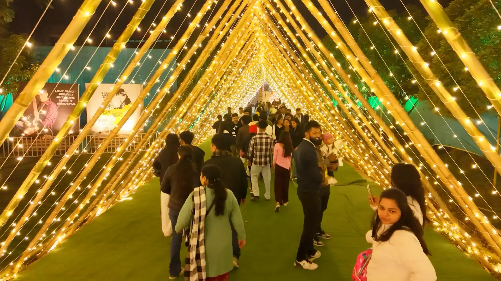 Illuminated fairy-light walkway with visitors between food and experience zones